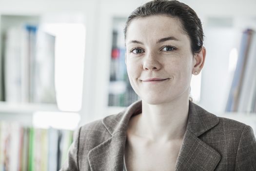 Portrait of smiling young businesswoman looking at the camera, head and shoulders