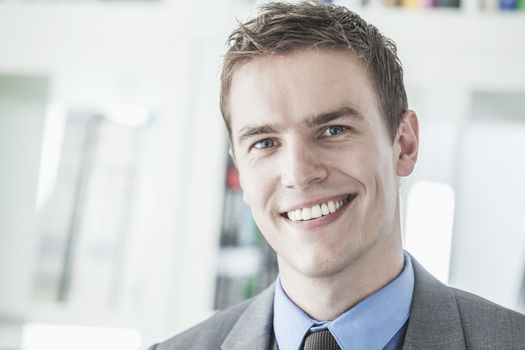 Portrait of young smiling businessman looking at camera, head and shoulders