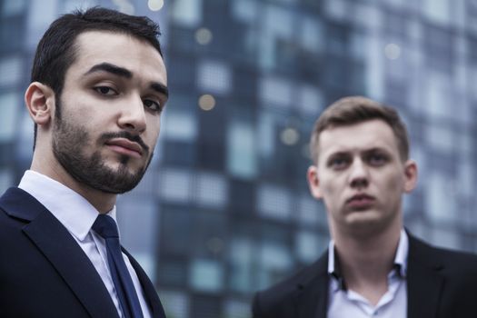 Portrait of two serious young businessmen looking at the camera, outdoors, business district