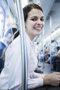 Portrait of young businesswoman sitting on the subway and looking at the camera