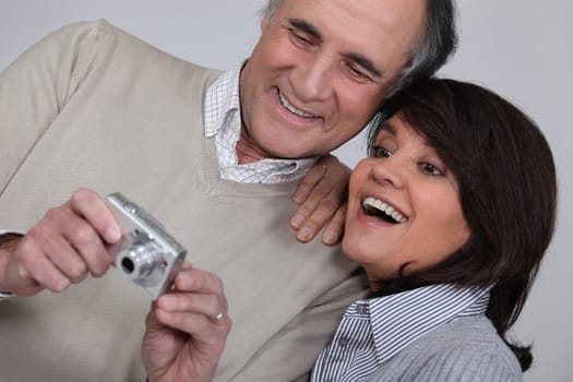 mature couple taking a picture of themselves with compact digital camera
