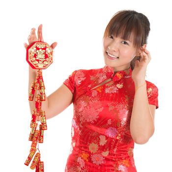 Pretty Asian woman with Chinese traditional dress cheongsam or qipao holding fire crackers. Chinese new year concept, the Chinese words means prosperity.