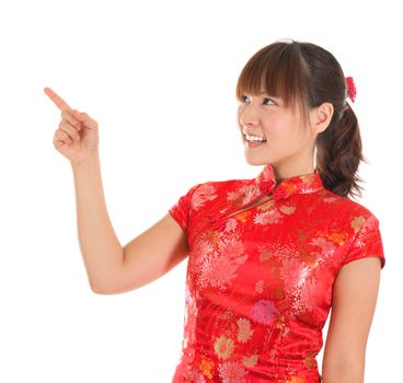 Pretty Asian woman with Chinese traditional dress cheongsam or qipao finger pointing at blank copy space. Chinese new year concept, female model isolated on white background.