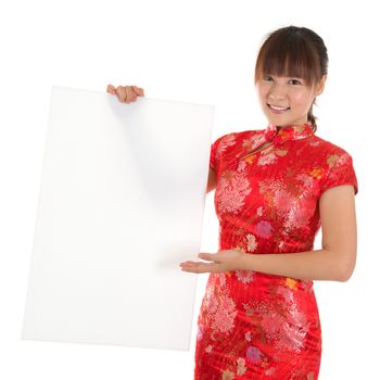 Asian woman with Chinese traditional dress cheongsam or qipao, holding blank white placard. Chinese new year concept, female model isolated on white background.
