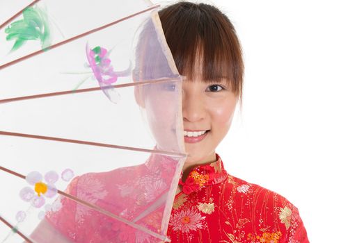 Asian woman with Chinese traditional dress cheongsam or qipao holding Chinese umbrella covering part of face. Chinese new year concept, female model isolated on white background.