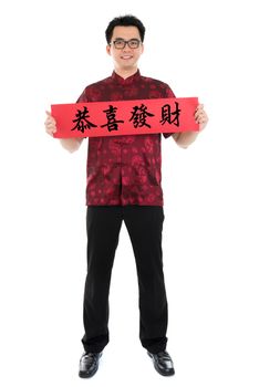 Full body Asian man with Chinese traditional cheongsam or tang suit holding couplet, the Chinese word means congratulations and best wishes for a prosperous New Year.  Male model isolated on white background.