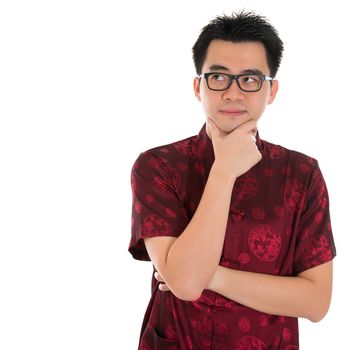 Asian man with Chinese traditional cheongsam or tang suit having a thought.  Male model isolated on white background.