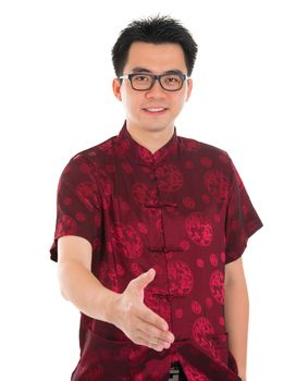 Asian man in traditional Chinese Cheongsam or Tang suit extending hand to give a handshake, standing isolated on white background. Asian male model.