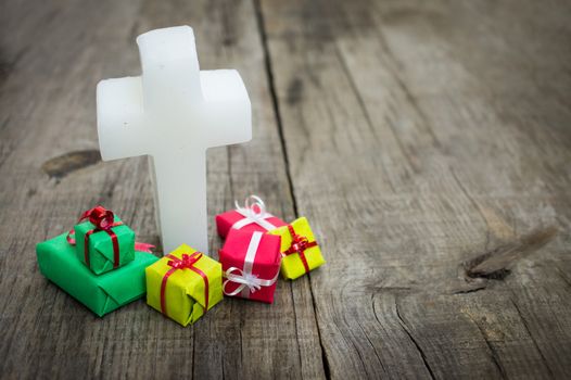 Religious cross with presents on wood background.