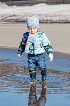 Little boy goes on a pool in rubber boots
