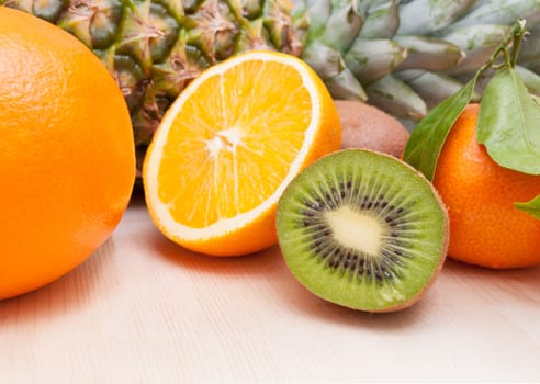 Tropical Fruits - Pineapple, Oranges, Tangerine and Kiwi on Wooden Table With Copyspace