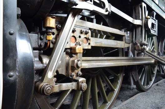 close up shot of a steam train showing its wheels and connecting rods.