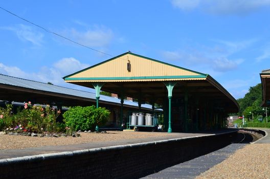 Victorian English train station platform in a rural countryside setting.