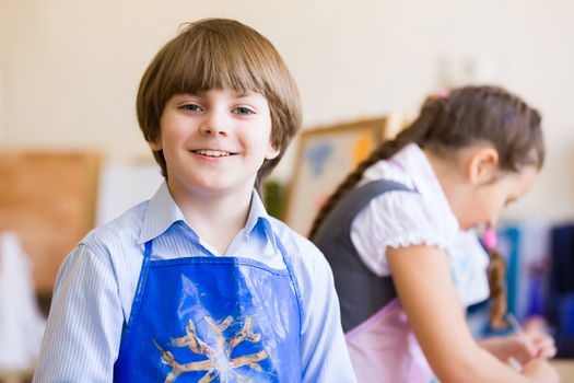 Image of little cute boy painting pictures at kindergarten