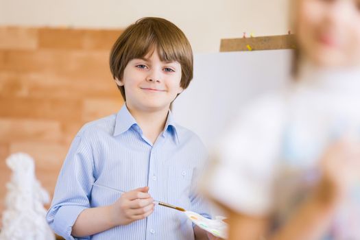 Image of little cute boy painting pictures at kindergarten