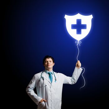 Young male doctor holding balloon with medical sign