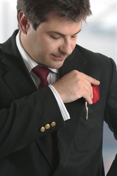 A smartly dressed man putting a business card, credit card or other type of  card into his top jacket pocket.