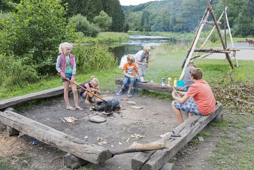 children having fun and making popcorn on the campfire