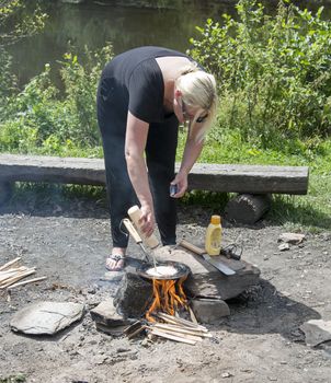 woman baking  pancake on the burning campfire