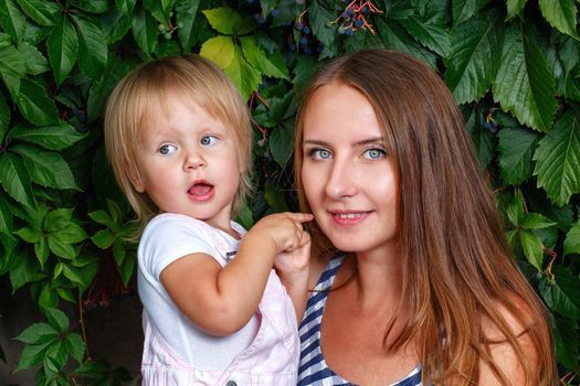 Mother holds daughter on hands on a background of city park