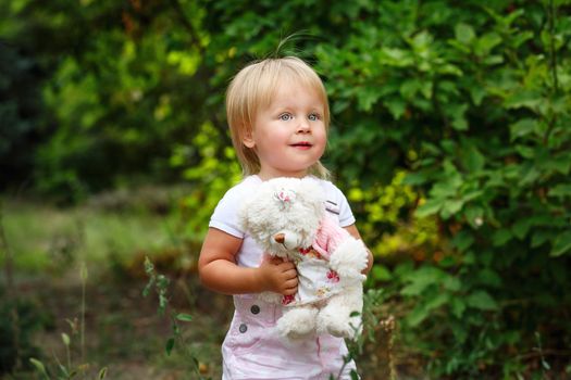 Blond girl with blue eyes holding a teddy bear
