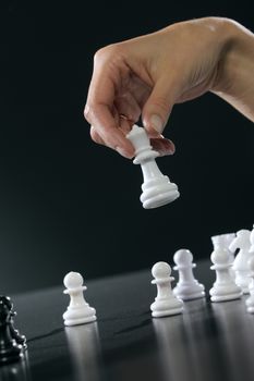 Female hand moving the queen in a chess game.