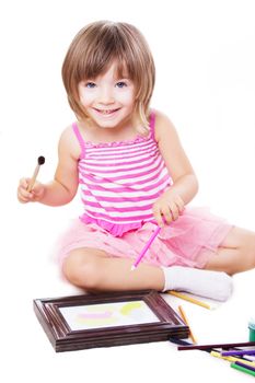 Smiling three year girl drawing over white