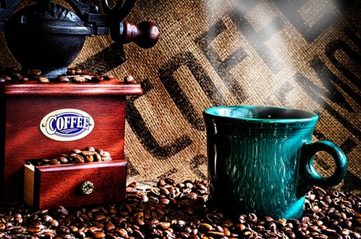 This image is a closeup of a cup of steaming hot coffee with coffee beans, coffee grinder, and coffee beans bag in background.