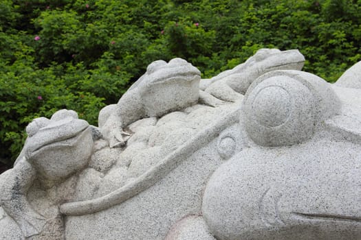 Stone frog sculpture on natural forest background