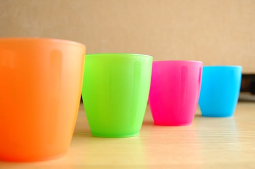 Four Colourful plastic mugs standing on floor