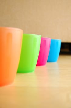 Four Colourful plastic mugs standing on floor