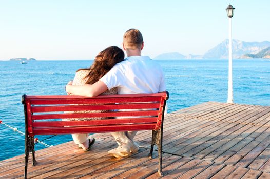 love couple sitting on a bench by the sea embracing