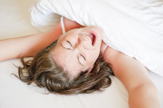 girl in a white bed yawns and stretches in the morning