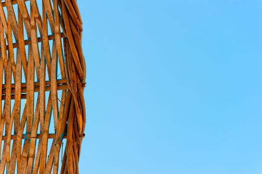 woven straw of a beach umbrella on a clear blue sky