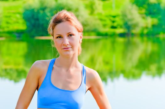 portrait of a beautiful girl on the nature of sports on the lake background