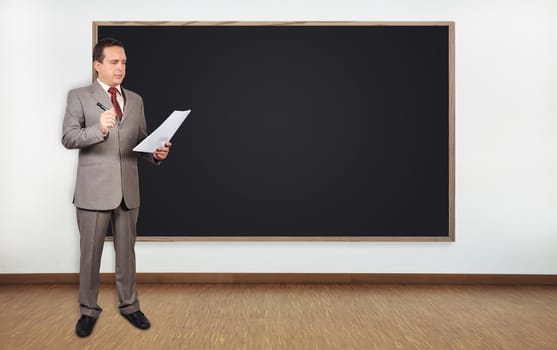 businessman standing in office and blank blackboard on wall