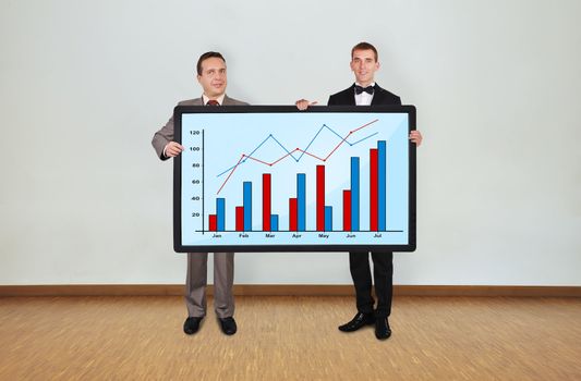 two businessman in room holding plasma panel with graph