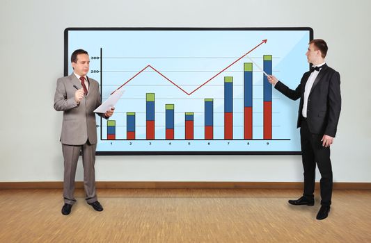 two businessman in office and chart on plasma panel