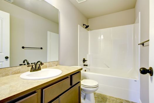 New home bathroom  interior with shower and bath combination, wood cabinet and toilet.