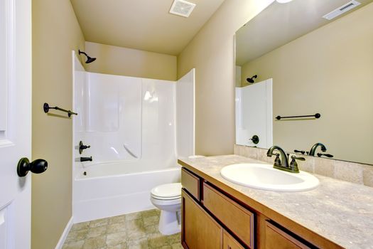 New home bathroom  interior with shower and bath combination, wood cabinet and toilet.