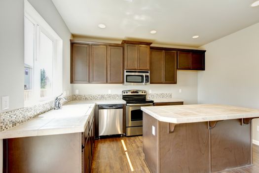 New home kitchen interior with dark brown cabinets and hardwood floors.