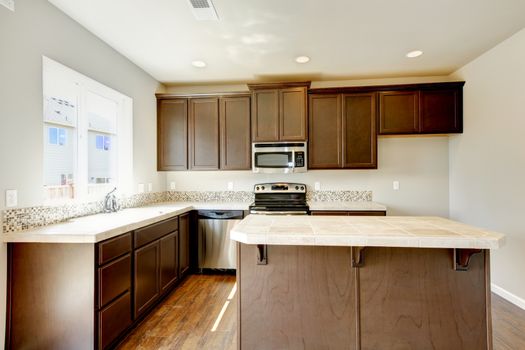 New home kitchen interior with dark brown cabinets and hardwood floors.