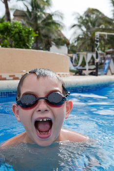 Kid having blasting fun in the swimming pool with his goggles on