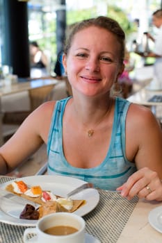 Beautiful lady having crepes along with her coffee in a breakfast place