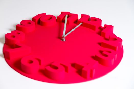 Red clock on isolated white showing five minutes to midnight