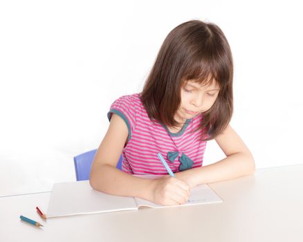 Child at desk with pencils and notebook