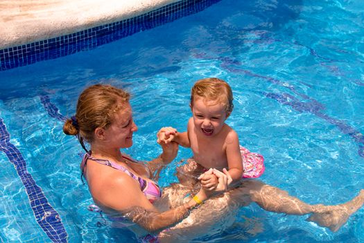 Mother and daughter in the swimming pool holding eachother, having fun time