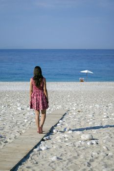 Girl on a beach walking towards beach relax place.