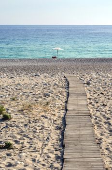 Wooden pathway through sandy beach to beach rest place.