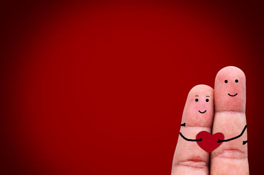 Happy couple in love with painted smiley holding red heart